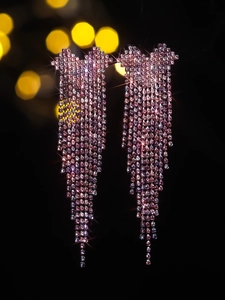 Macro view of luxurious rose pink crystal fringe earrings with sparkling tassel detail