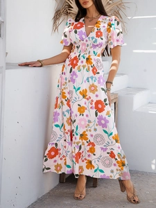 Detail of pink V-neck maxi dress with vintage floral print and puff sleeves in Mediterranean setting