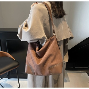 Detail of brown suede tote bag featuring reinforced leather bottom and white stitching