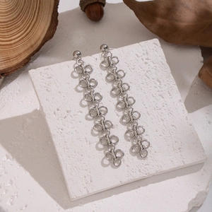 Détail de boucles d'oreilles trèfle en argent avec maillons sur fond de pierre blanche