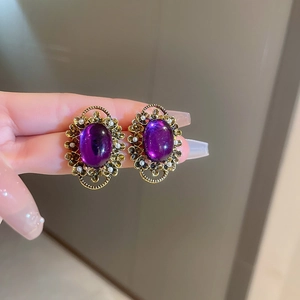 Close-up of vintage gold ear cuff with oval purple gemstone and pearl accents