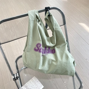 Détail du sac fourre-tout gaufré vert menthe avec impression du logo Saliko violet