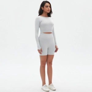 Detail eines hellgrauen nahtlosen Fitness-Sets mit Langarm-Crop-Top und Yoga-Shorts