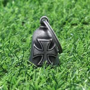 Detail view of a vintage stainless steel biker bell pendant with embossed Iron Cross on grass