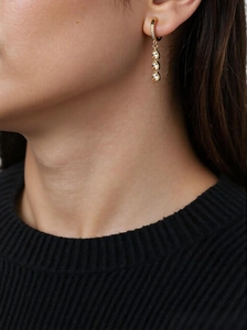 Detail of gold tassel earrings with teardrop gems on a black knit sweater