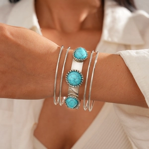 Detail of bohemian layered silver bracelets featuring turquoise stones and intricate engraving