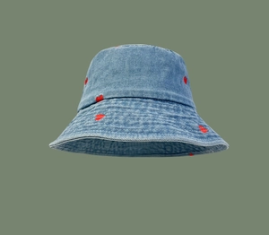 Detail shot of red heart embroidery on light blue denim fabric of a fisherman hat