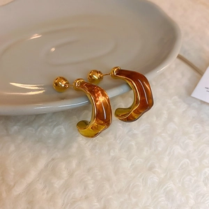 Retro amber brown resin C-shaped earrings with gold metal accents on white faux fur background