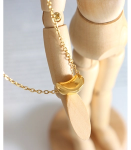 Macro shot of a vintage golden bean pendant necklace on a wooden mannequin stand