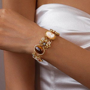 Detailansicht eines Vintage-Cameo-Armbands mit Harzblumen und Steinen am Handgelenk einer Frau