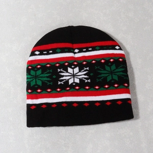 Detail of Christmas knitted beanie with red and white snowflake patterns on black fabric