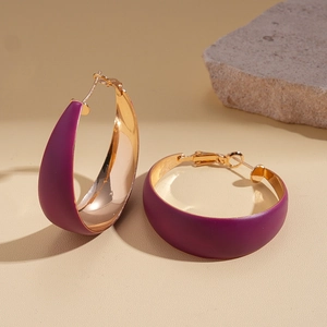 Close-up of geometric C-shaped earrings with purple matte finish and gold interior