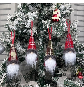 Detail of colorful gnome ornaments hanging on a snowy Christmas tree branch