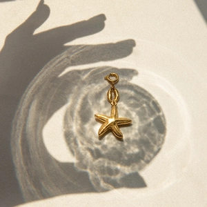 Detailed view of a gold starfish pendant with a shell pearl and round spring clasp