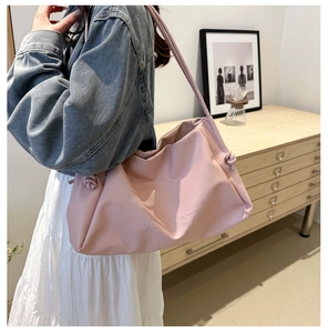 Detail of pink faux leather tote bag showing side knot design and embossed logo