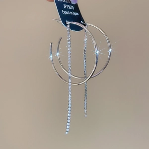Dettaglio di orecchini a cerchio in argento con lunghe nappe brillanti e marchio 925