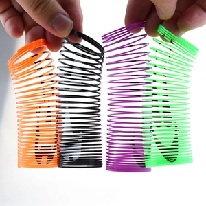 Close-up of four colorful Halloween slinky toys being stretched with pumpkin prints