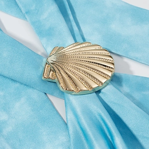 Detailed close-up of a decorative gold shell pendant with light blue satin straps