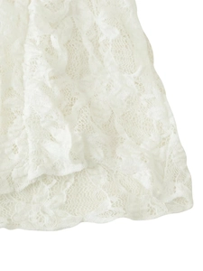 Close-up of white lace hem with delicate knit patterns and intricate floral hollow texture