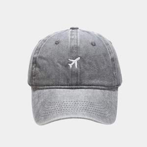Détail de la broderie d'avion blanche sur une casquette de baseball en coton gris délavé