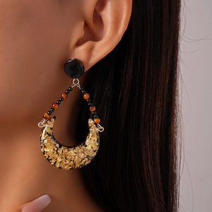 Detail of vintage teardrop earrings with gold foil in resin on a female model