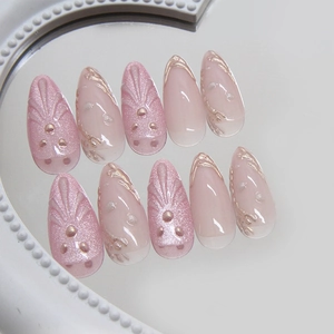 Elegant 3D shell press-on nails with gold lines and pearl accents on a round mirror