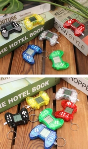 Mini retro handheld game console keychain in various vibrant colors on a wooden desk