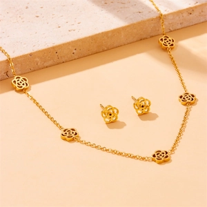 Golden five-leaf flower necklace and stud earrings set on a warm stone background