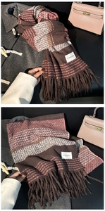 Detailed close-up of thick brown and pink plaid scarf texture with tassel accents