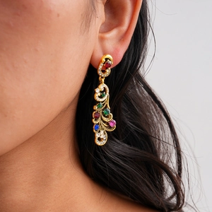 Gros plan de boucles d'oreilles paon vintage dorées avec zircons colorés sur un modèle