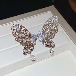 Vue détaillée du clip d'oreille papillon évidé avec zircons et perles blanches nacrées