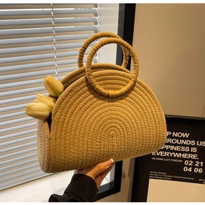 Detailed view of natural straw semi-circular woven handbag with round handles on display