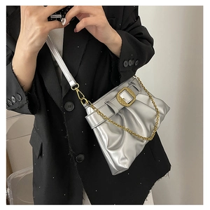 Détail du sac argenté métallisé froncé avec boucle dorée sur un blazer noir chic