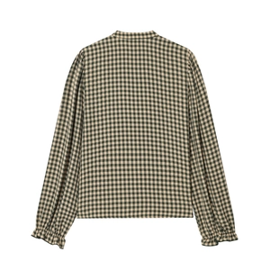 Detail of checkered blouse featuring puff sleeves and ruffled elastic cuffs on fabric