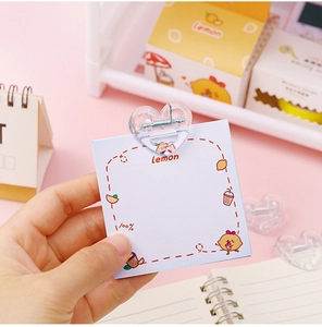 Close-up of a cute transparent heart-shaped plastic clip holding a lemon patterned memo card
