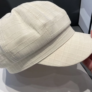 Detail of beige newsboy cap showing textured plaid jacquard fabric and structure