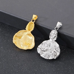 Close-up of gold and silver Saint Jude religious pendants on a dark textured surface