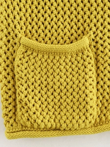 Dettaglio ravvicinato del gilet in maglia giallo senape con trama e tasca
