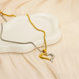 Detail of hollow asymmetric heart pendant with two-tone gold and silver beaded chain