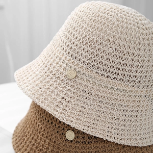 Detail of breathable knit bucket hats with golden metallic logo in beige and brown colors