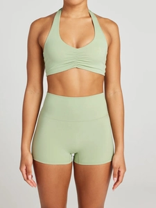 Detail view of light green halter neck sports bra with ruched front and high waist shorts