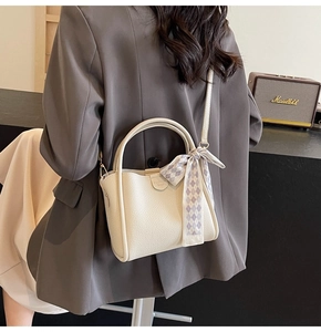 Detail of white lychee texture bucket bag with plaid silk scarf tied on the handle