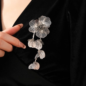 Detail of silver floral brooch with white rhinestones and tassels on black velvet clothing