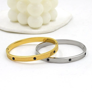 Detail of gold and silver steel bracelets featuring mesh texture and black stone inlays