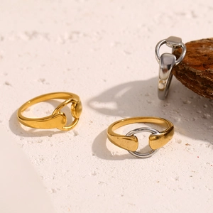 Macro detail of 18K gold plated horsebit buckle rings on a natural stone surface