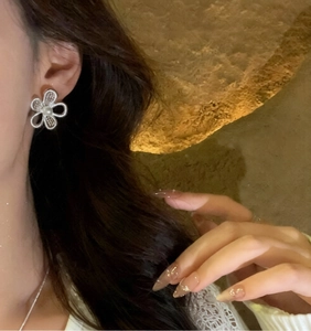 Detailed macro view of silver hollow flower stud earrings with a central white pearl