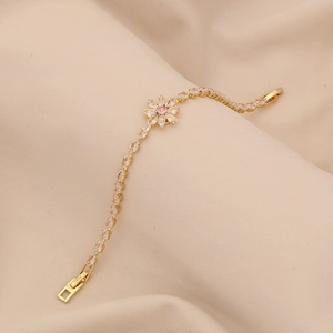 Close-up of gold-plated bracelet with marquise zircons and pink flower centerpiece