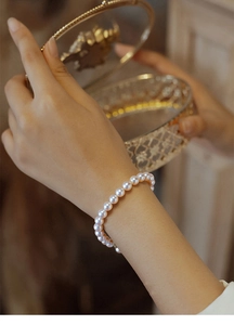 Detail of vintage pearl bracelet on wrist holding a retro golden jewelry box