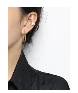 Detail of gold irregular lava texture earring and pearl ear cuff on a female model
