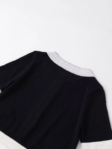 Detail of contrast white trim on black crew neck knit jacket with textured fabric